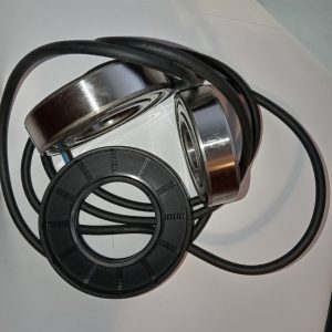 Black over-ear headphones with metal silver rims resting on a white surface, cable looping around them.
