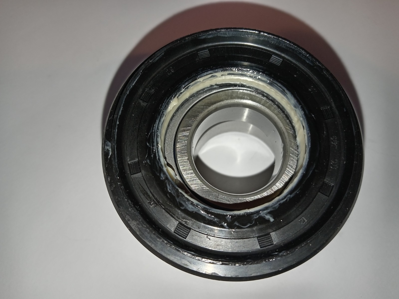 s-l1600-339.jpg Close-up of a metal bearing with white grease around the inner race and seal places the grease.