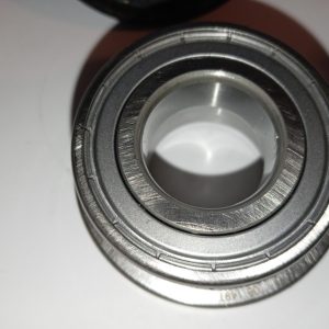 Close-up of a metallic bearing showing outer ring, inner bore, and grooves in a shiny metal surface