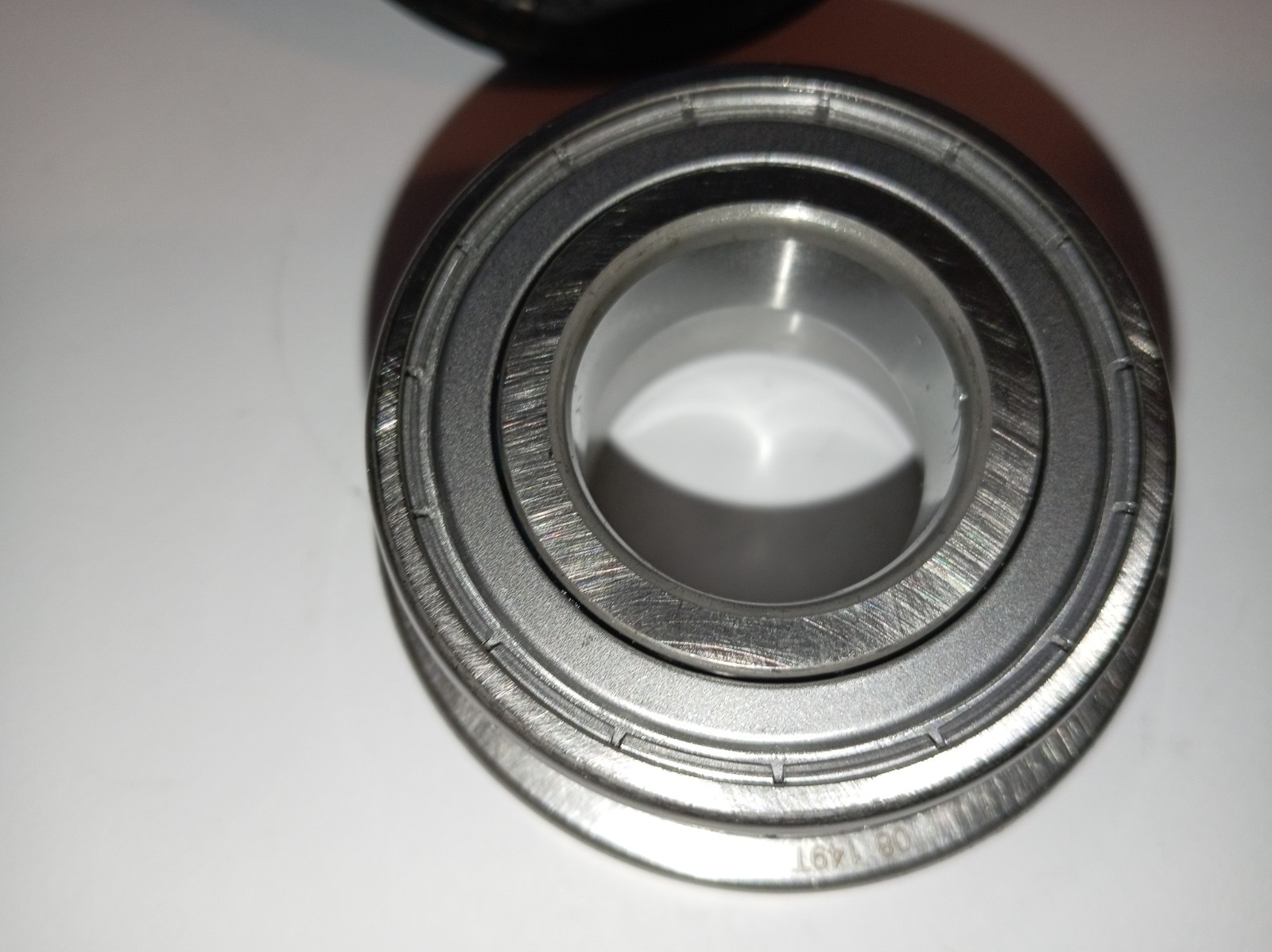 s-l1600-341.jpg Close-up of a metallic bearing showing outer ring, inner bore, and grooves in a shiny metal surface