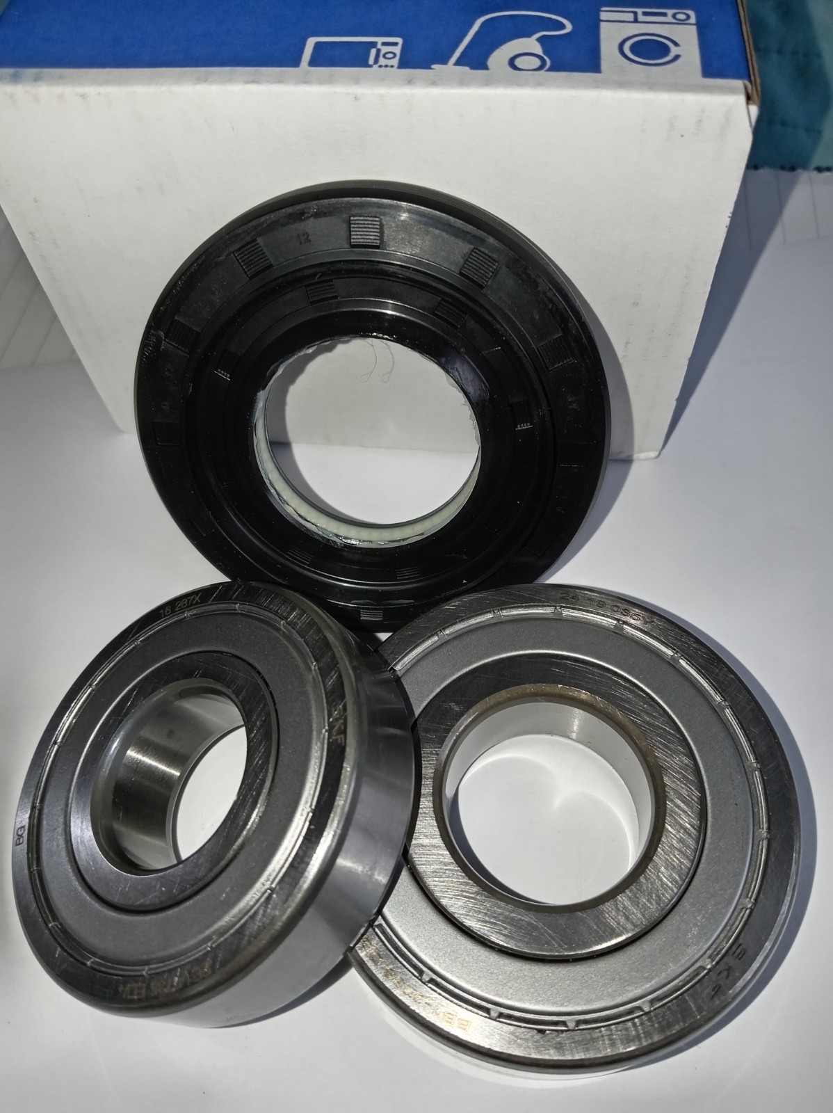 s-l1600-343.jpg Set of three ball bearings on a white surface in front of a white box with blue print; two silver bearings and one black-coated bearing visible from the front.