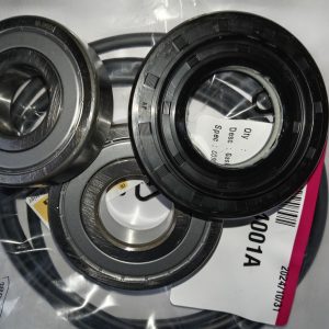 Close-up of multiple metal bearings and seals on a clear plastic bag with a label and barcode nearby, viewed at an angle.