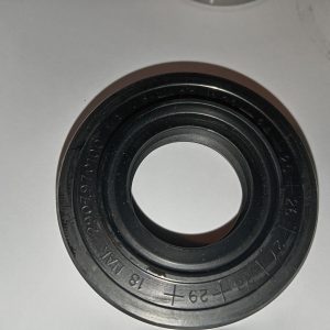 Black circular rubber seal or bearing with concentric rings and engraved numbers, resting on a white surface.