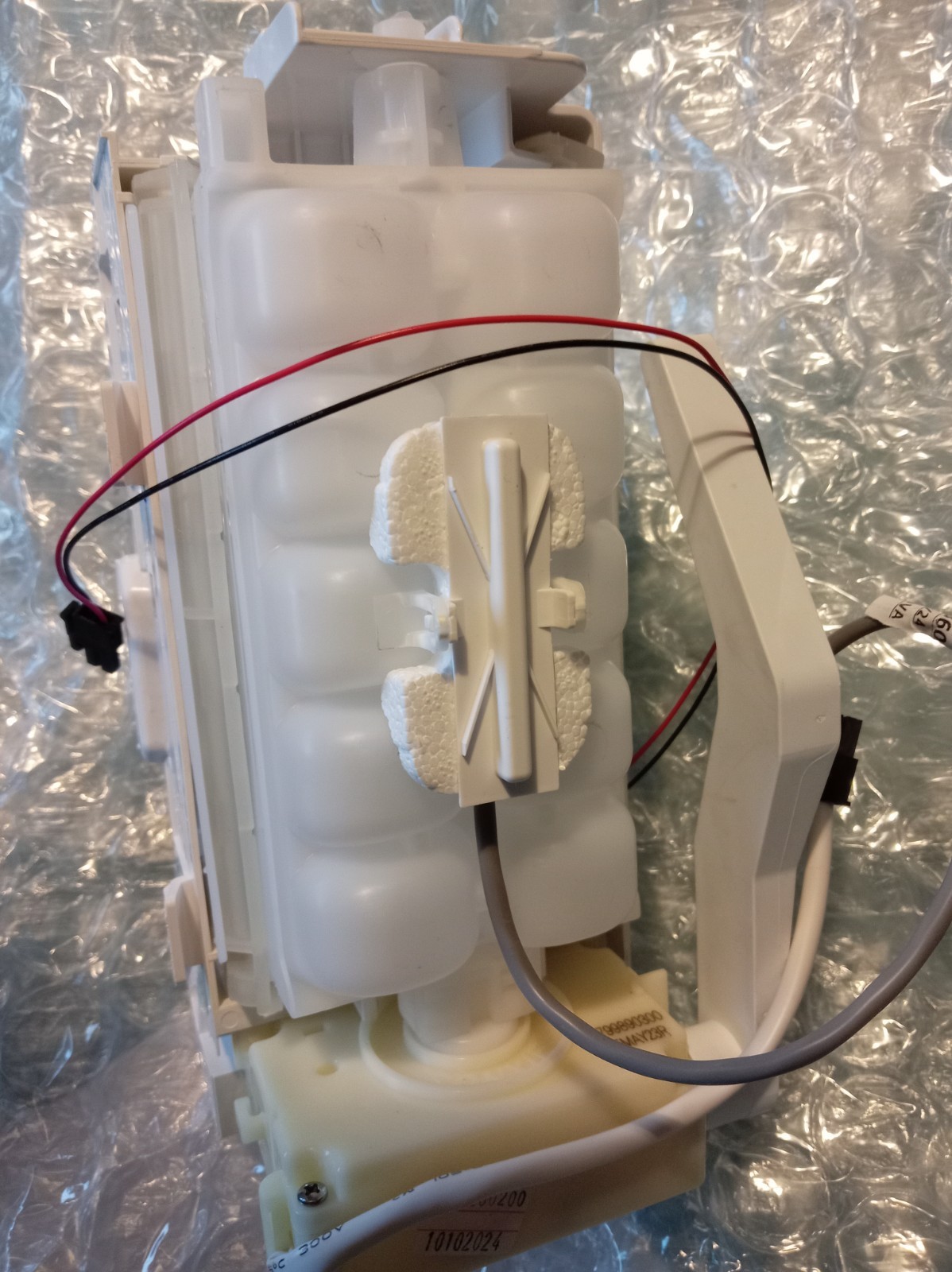 s-l1600-361.jpg White plastic appliance component with red and black wires, mounted on a frame with foam padding and a silver foil backdrop.