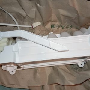 White plastic lever/arm assembly with a mounting bracket on brown paper, likely part of an appliance mechanism