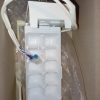 White plastic electrical module with multiple recessed sockets and a blue wire connector, packed in a cardboard box with packing film.