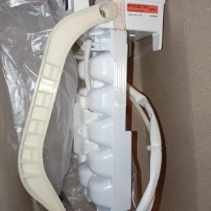 Close-up of a white medical device component with an orange model label, a beige curved grip, and a bundled cable in a cardboard box.