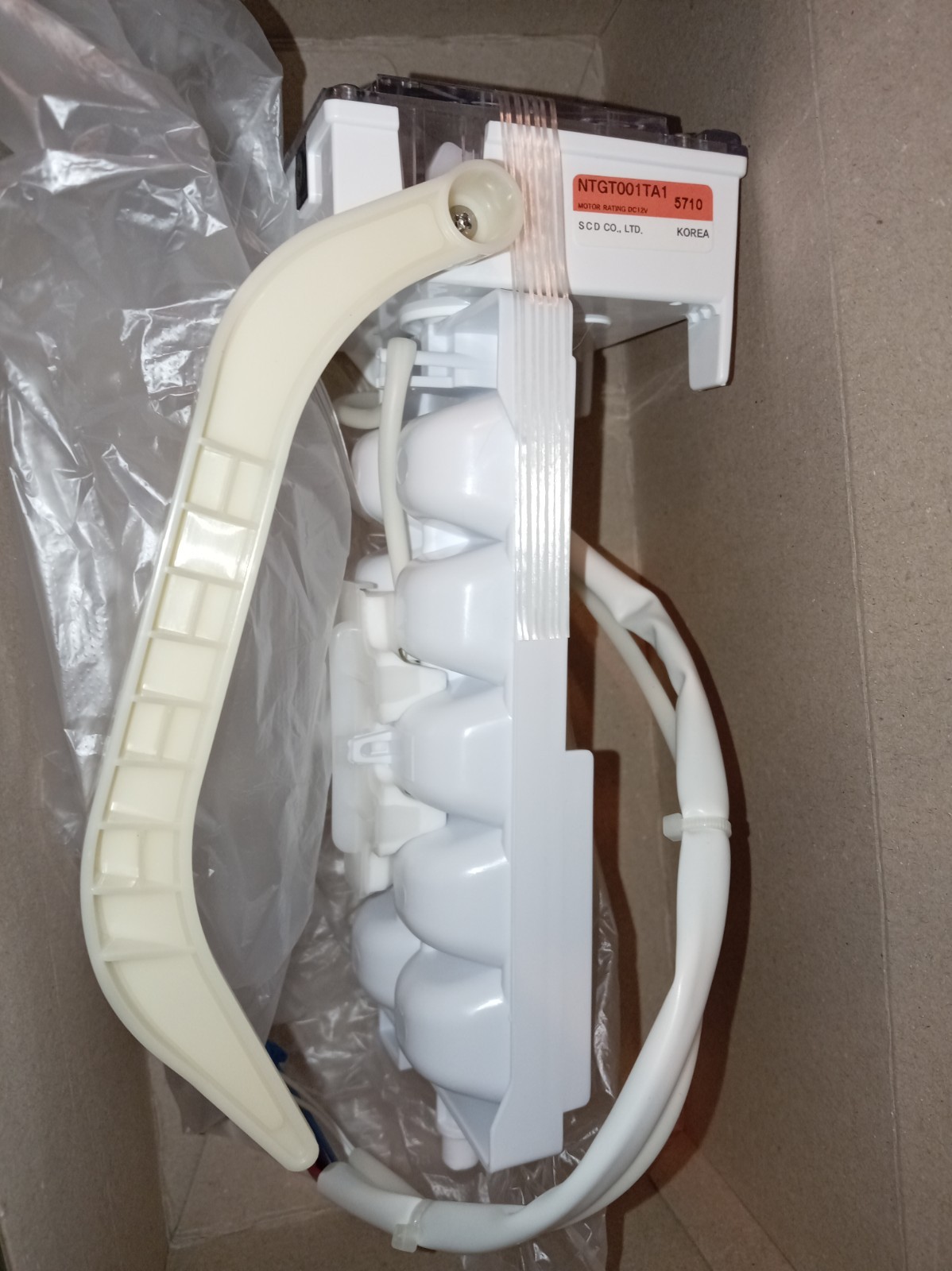s-l1600-377.jpg Close-up of a white medical device component with an orange model label, a beige curved grip, and a bundled cable in a cardboard box.