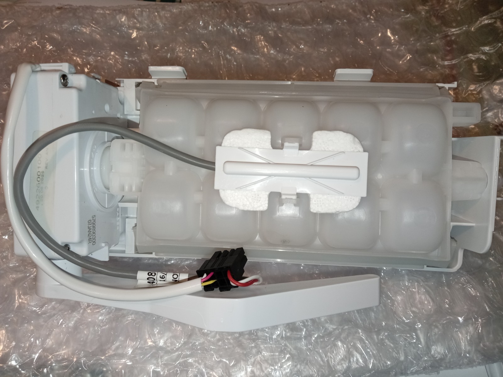 s-l1600-382.jpg Internal view of a white plastic appliance module with foam padding, a sliding white piece, gray wiring harness, and a black connector.