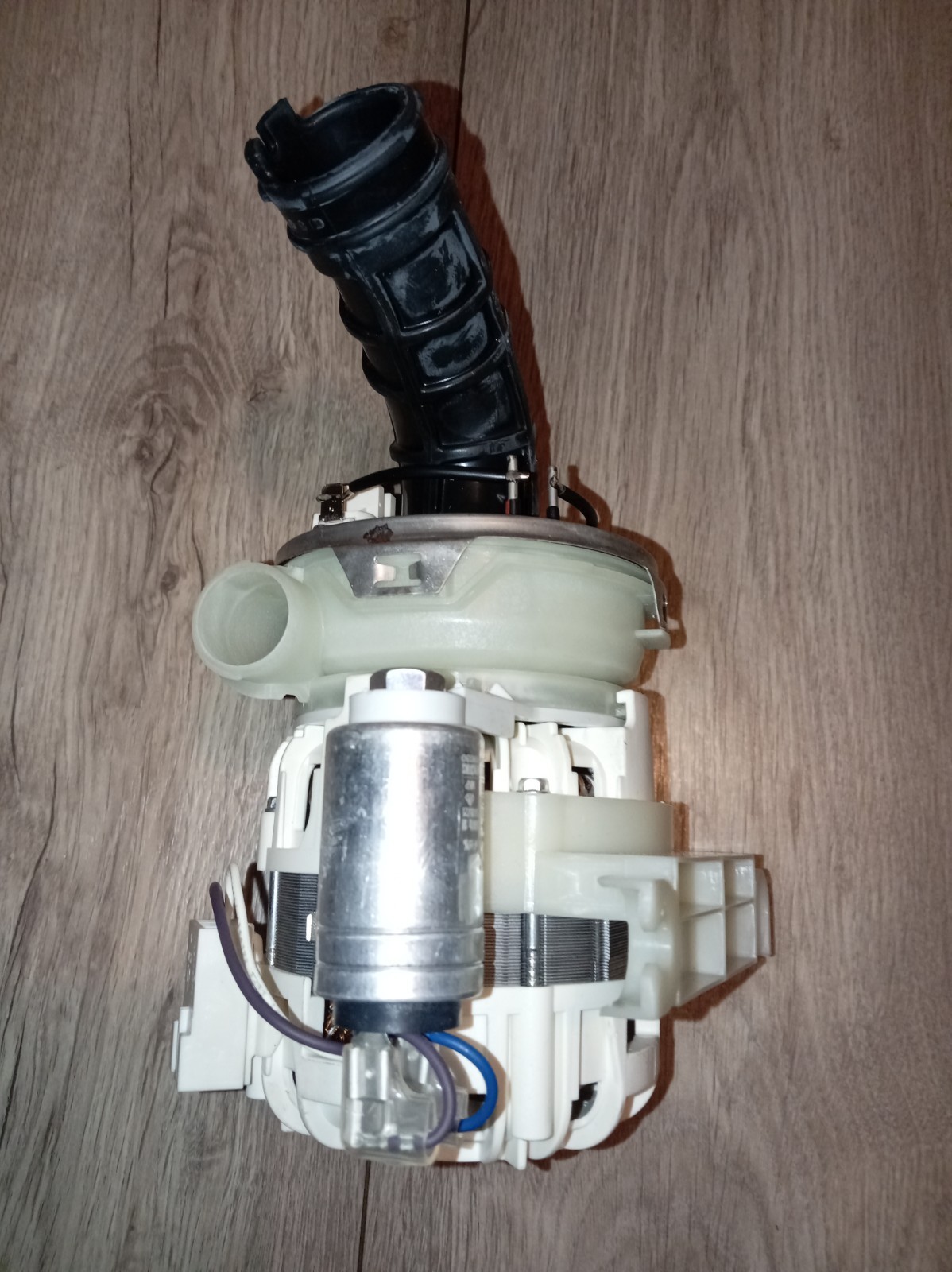 s-l1600-398.jpg Disassembled appliance pump with a black flexible outlet hose, white plastic housing, metal motor, and blue wires on a wooden floor