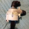 White plastic pump assembly with two black hose fittings attached, lying on a quilted blue surface.