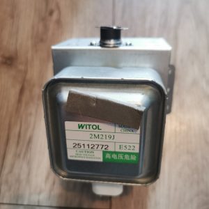 Close-up of a WITOL high-voltage microwave transformer with a metal enclosure and a small top connector, placed on a wood floor.