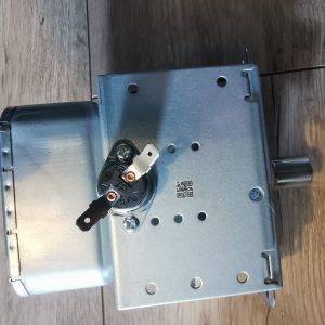 Metal electrical enclosure with a circular terminal block and two copper terminal screws mounted on the side, on a wooden surface.