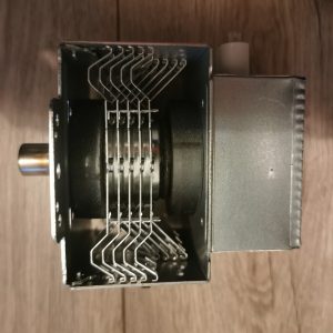 Close-up of a metal mechanical component with a protruding shaft on the left and curved wire springs inside a metal box.