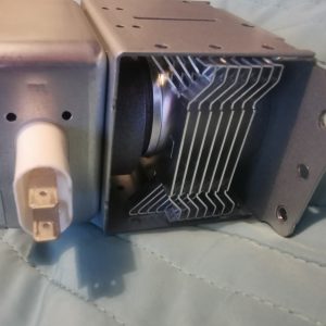 Metal HVAC blower housing with a curved-fin heat exchanger visible inside a rectangular enclosure and a round duct on the left.