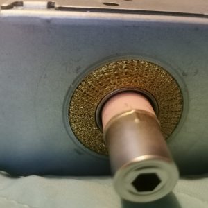 Close-up of a copper pipe passing through a circular brass mesh filter inside a gray metal housing.