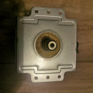 Metal square machine component with a central circular bore surrounded by a textured ring and multiple small holes on a perforated flange.