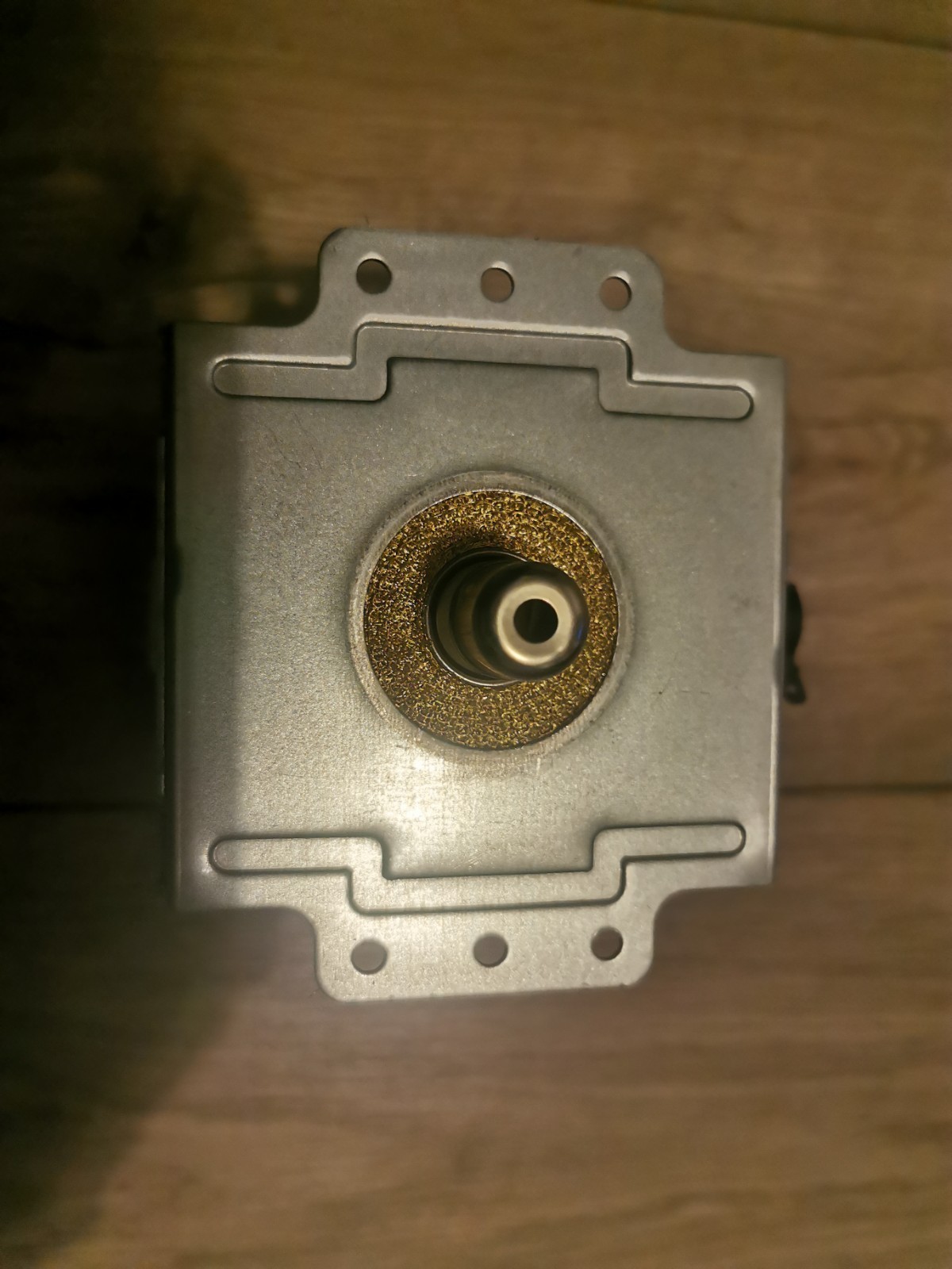 s-l1600-662.jpg Metal square machine component with a central circular bore surrounded by a textured ring and multiple small holes on a perforated flange.