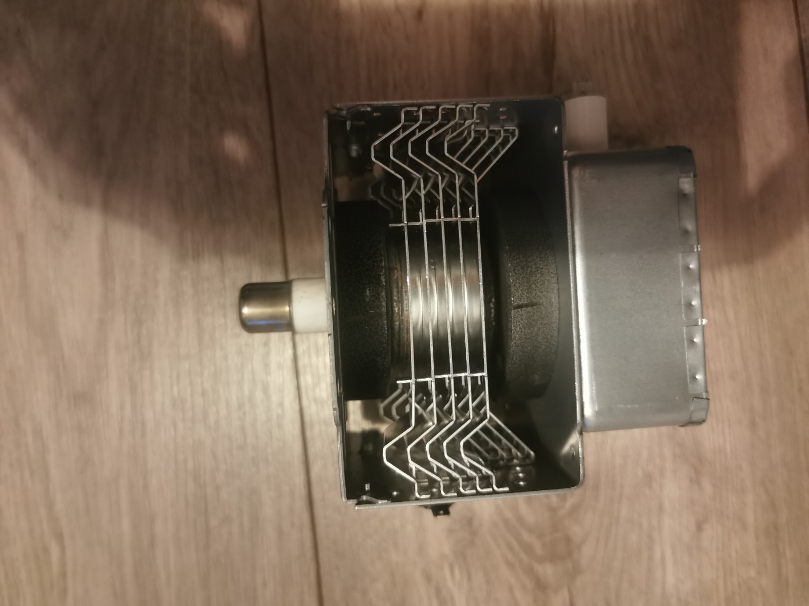 s-l1600-663.jpg Close-up of a small metal mechanical assembly with a bundle of vertical metal fins and a right-side metallic housing, mounted on a wooden floor surface.
