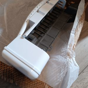 White plastic electrical module with a multi‑color wire harness and yellow connector, resting on packaging material