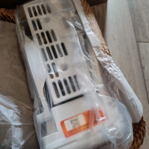 White rectangular electronic device with vent slots, wrapped in plastic inside a cardboard box.