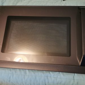 Top-down view of a Toshiba microwave oven with the interior perforated metal panel visible inside a dark frame, door closed.