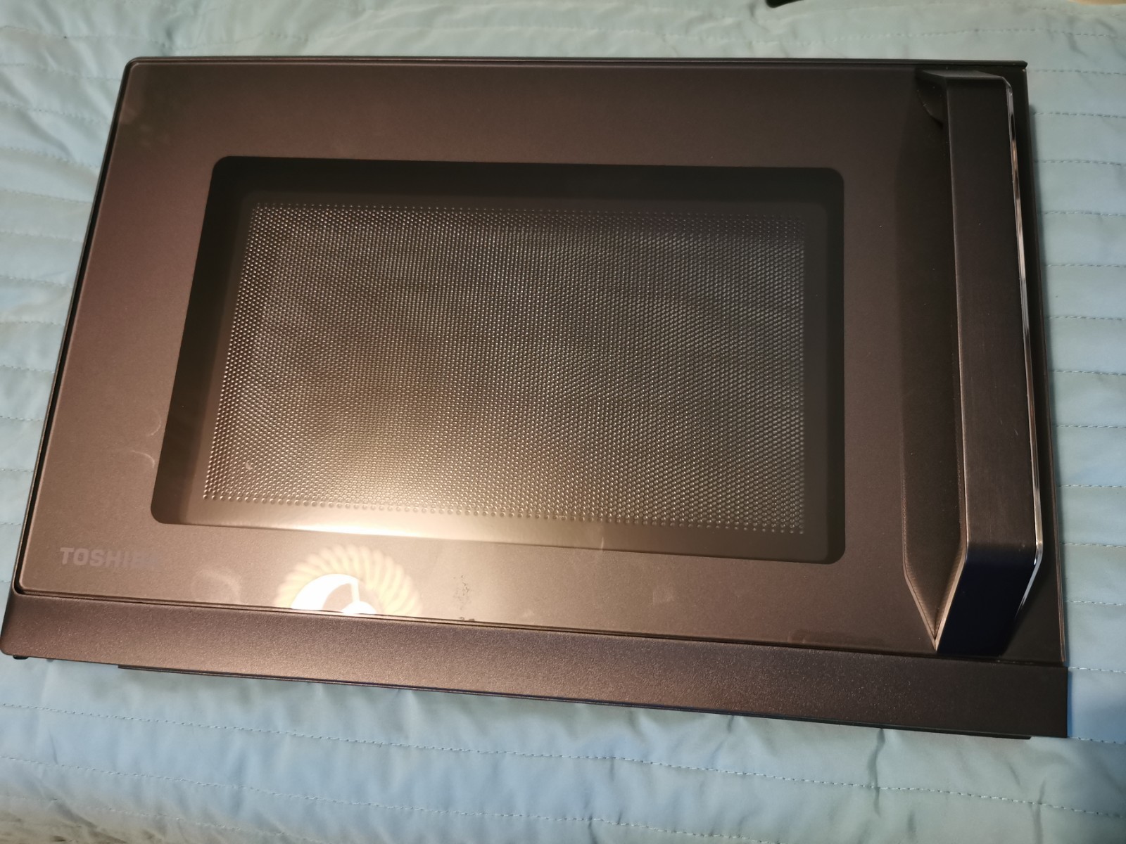 s-l1600-702.jpg Top-down view of a Toshiba microwave oven with the interior perforated metal panel visible inside a dark frame, door closed.