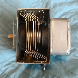 Close-up of a small electric motor showing stacked metal laminations and a shaft extending from the left.