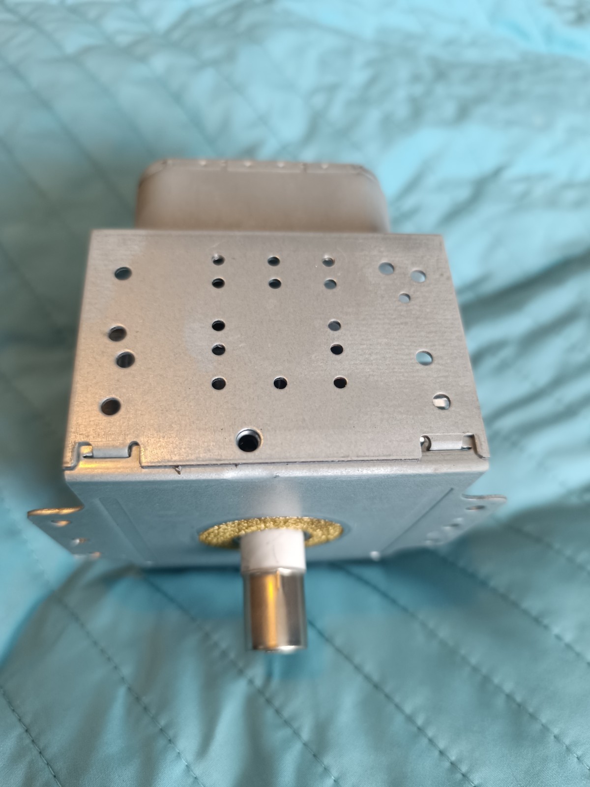 s-l1600-791.jpg Metal rectangular electronic component with a perforated top and a cylindrical shaft protruding from the bottom, placed on a blue quilted surface.