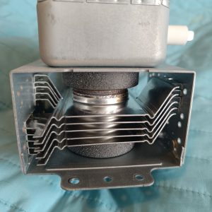 Industrial metal coffee roaster component with a rectangular housing atop an open chamber and curved wire cooling racks inside, set against a blue background