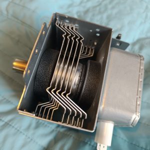 Close-up of a metal tool with stacked curved blades in a square housing attached to a motor.