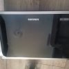 Samsung microwave oven with black glass door, silver trim, and Ceramic Inside label on the right side.