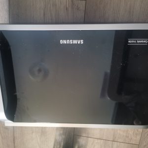 Samsung microwave oven with black glass door, silver trim, and Ceramic Inside label on the right side.
