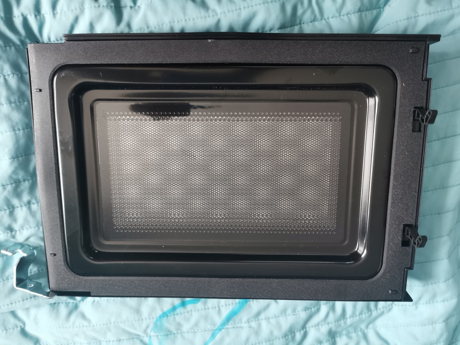 s-l1600-885.jpg Black oven/microwave door with a perforated inner panel laid on a teal quilted surface.