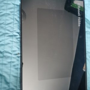 Russell Hobbs tablet-shaped kitchen appliance panel lying on a blue quilted surface, reflective screen facing up