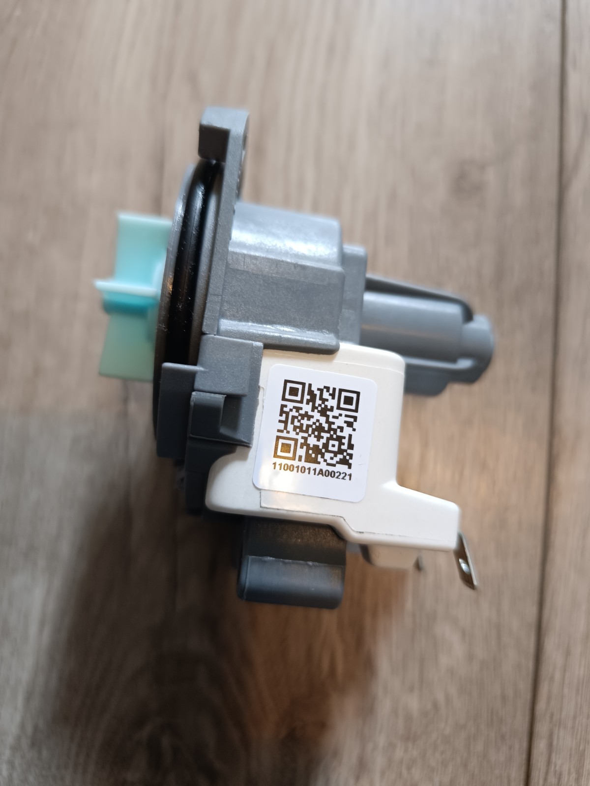 s-l1600-906.jpg Close-up of a gray plastic mechanical component with a white label showing a QR code and serial number, placed on wood floor.