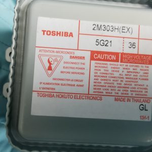 Close-up of a Toshiba microwave transformer label showing model 2M303H(EX) and high voltage caution text.