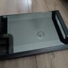 Toshiba flatbed scanner with glass lid lying on a wooden floor, reflection visible on glass surface.