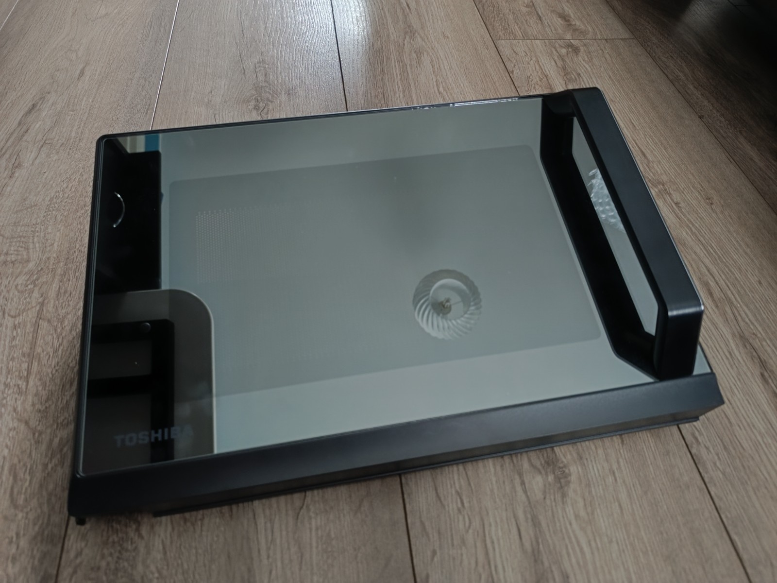 s-l1600-979.jpg Toshiba flatbed scanner with glass lid lying on a wooden floor, reflection visible on glass surface.