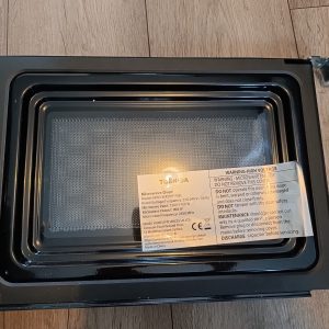 Top-down view of an open microwave oven, showing the interior cavity and a warning label on the door edge.